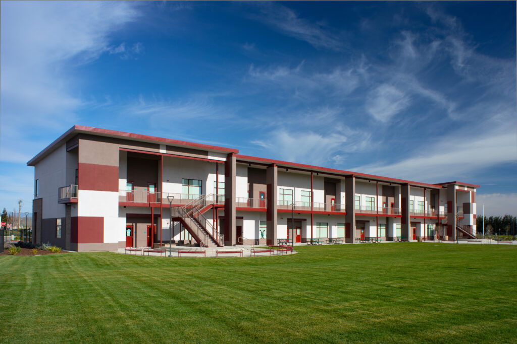 A wide view of the Greenfield High School modular building, showcasing the large green lawn in front and the classroom structure.