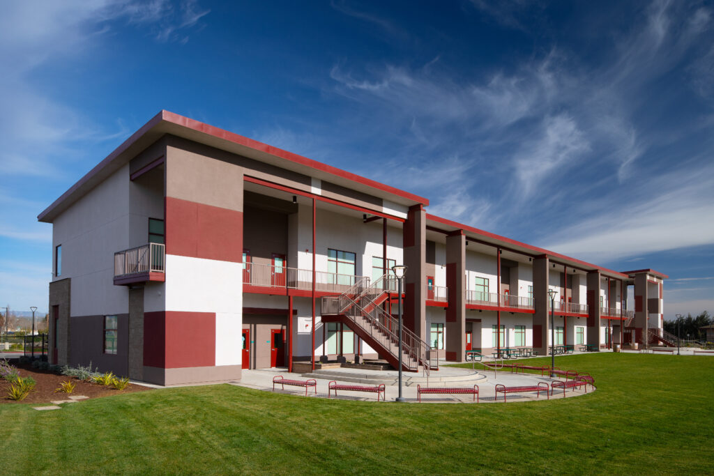 Exterior view of the Greenfield High School modular classroom building with outdoor seating areas and landscaped surroundings.