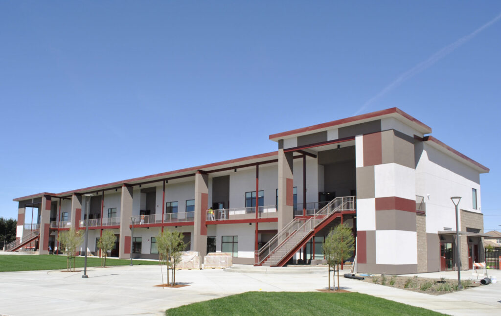 The two-story modular classroom building at Greenfield High School, surrounded by landscaped green lawns and walkways.
