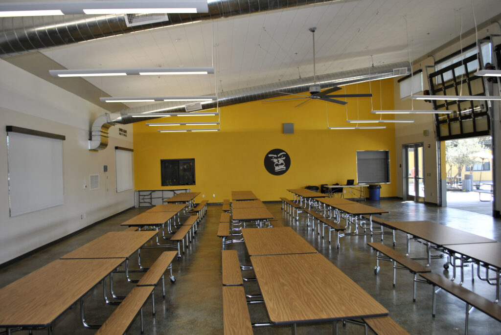 Interior of ACE Empower Academy's multipurpose building with tables set up in the cafeteria area.
