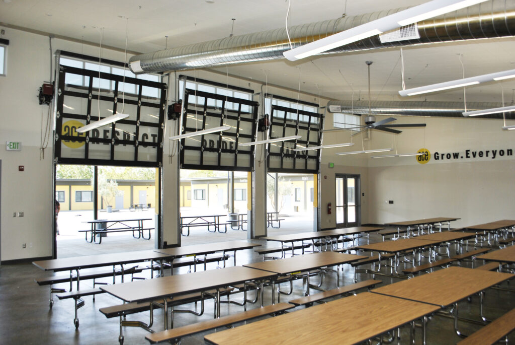 Interior of ACE Empower Academy's multipurpose building, highlighting roll-up doors for flexible access.