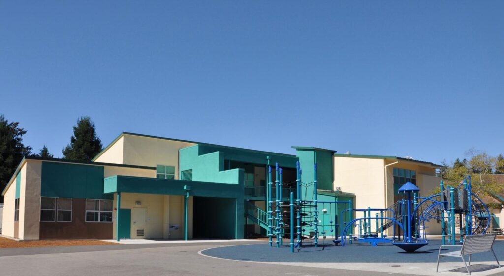 Front view of the new two-story classroom building at Main Street Elementary School, featuring modern design and playground facilities.