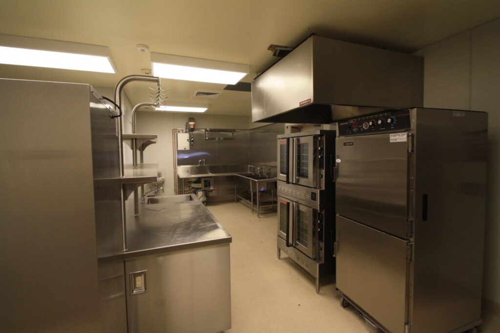 Warming kitchen in the multi-use building at Grace Patterson Elementary, equipped with modern appliances including ovens and stainless steel counters.
