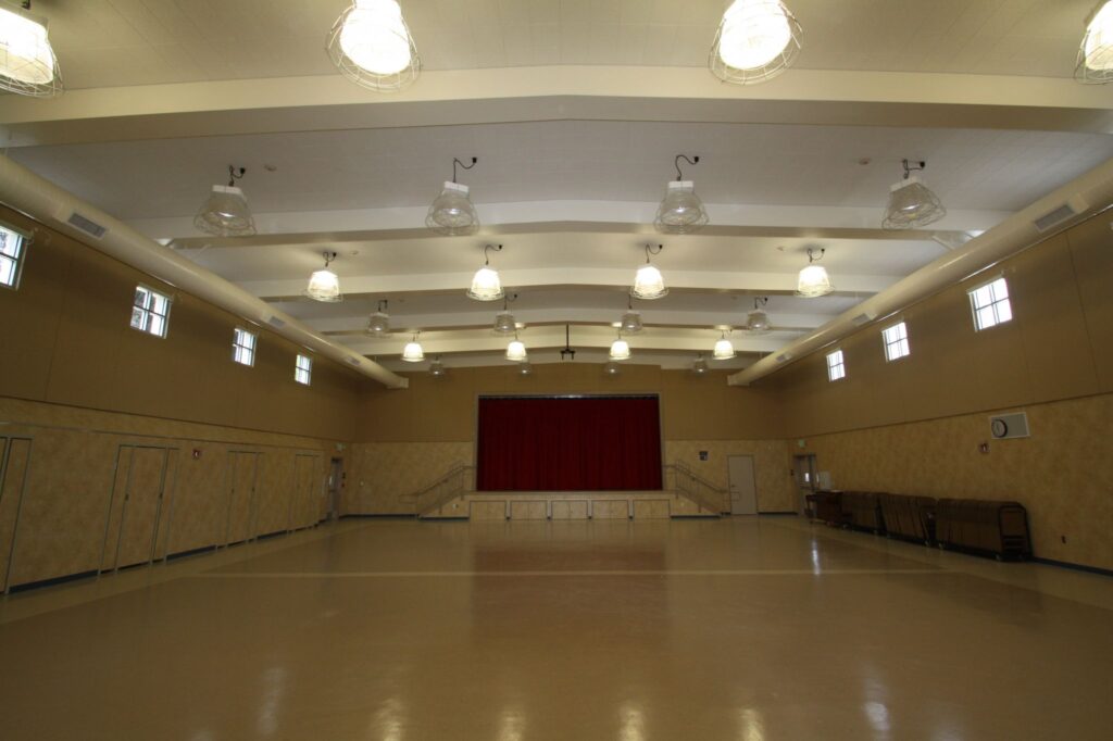 Interior of the multi-use building at Grace Patterson Elementary, featuring a spacious area with a stage for performances and events.