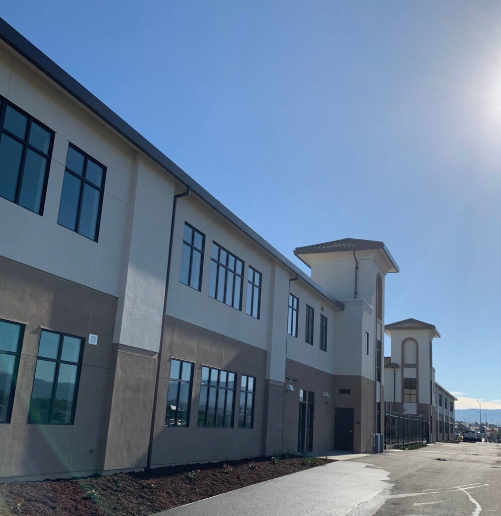 Sunlit view of Rancho Santana School’s modern modular buildings with tall windows and a sleek design.