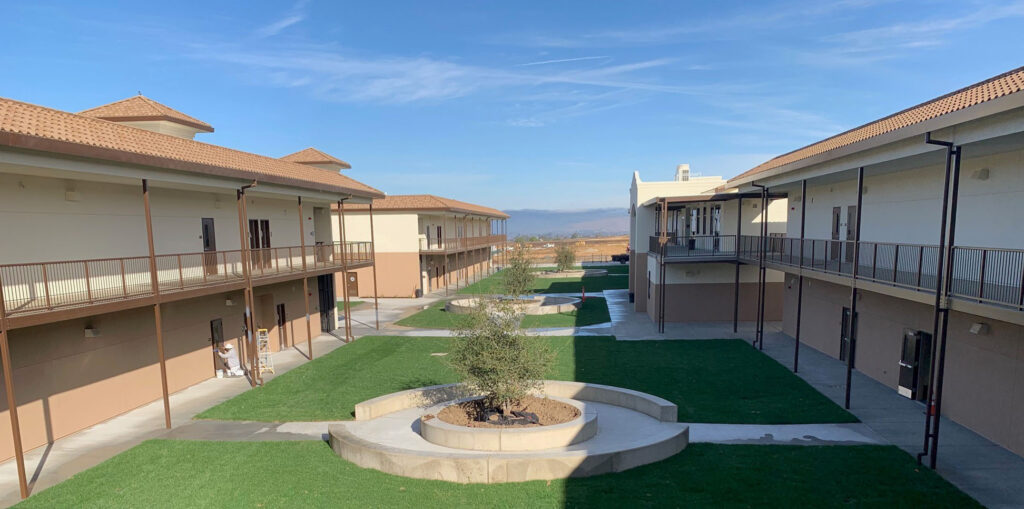 Wide view of the Rancho Santana School courtyard with two modular buildings and a landscaped center area with trees.