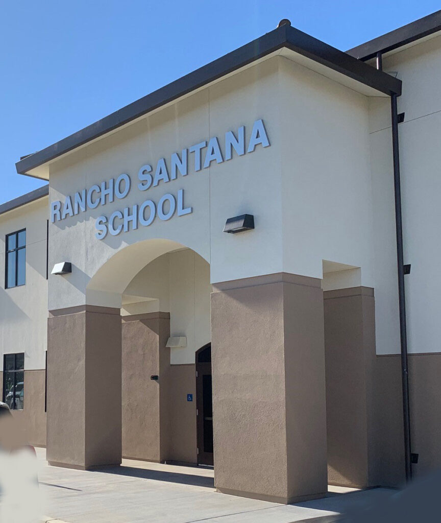 Rancho Santana School main entrance with bold signage, modern design, and modular construction.