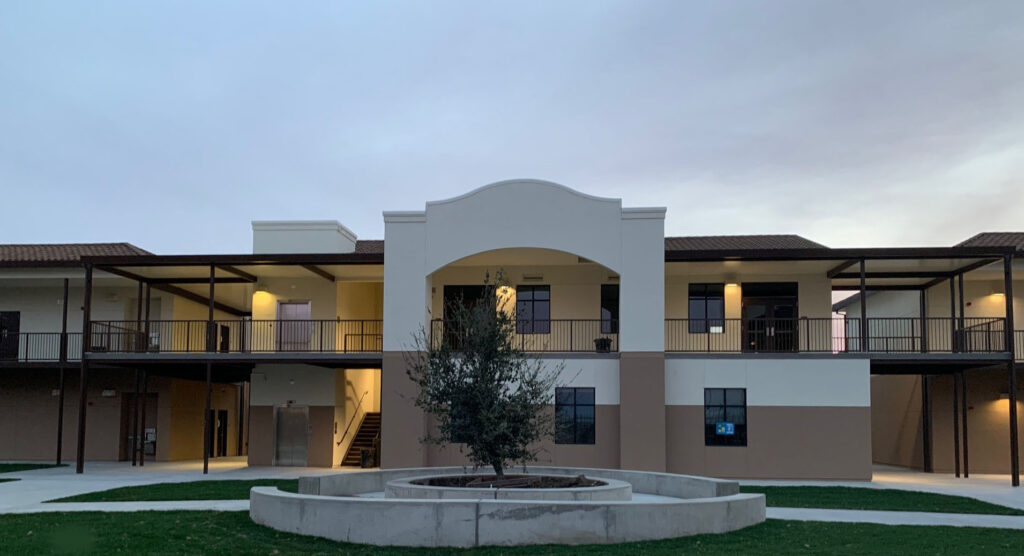 Front view of the Rancho Santana School courtyard, with a focus on the two-story modular buildings and central landscaping.