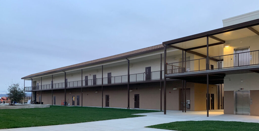 Side view of a two-story modular classroom building at Rancho Santana School, showcasing the long walkways and open space design.