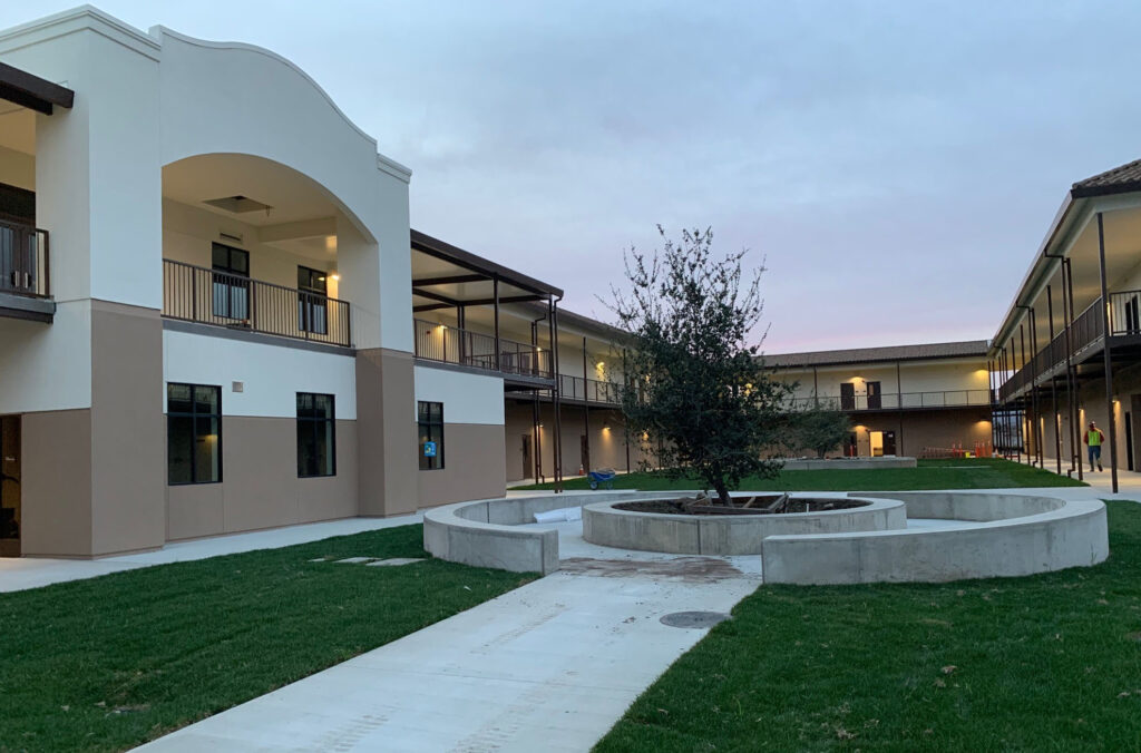 Evening view of the courtyard at Rancho Santana School, showing the modern two-story modular buildings with a landscaped central area.
