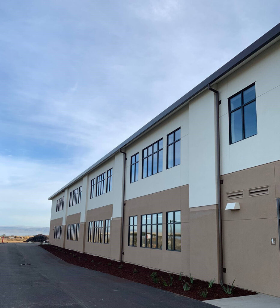 Exterior side view of Rancho Santana School’s modular building, featuring large windows and a sleek, modern design.