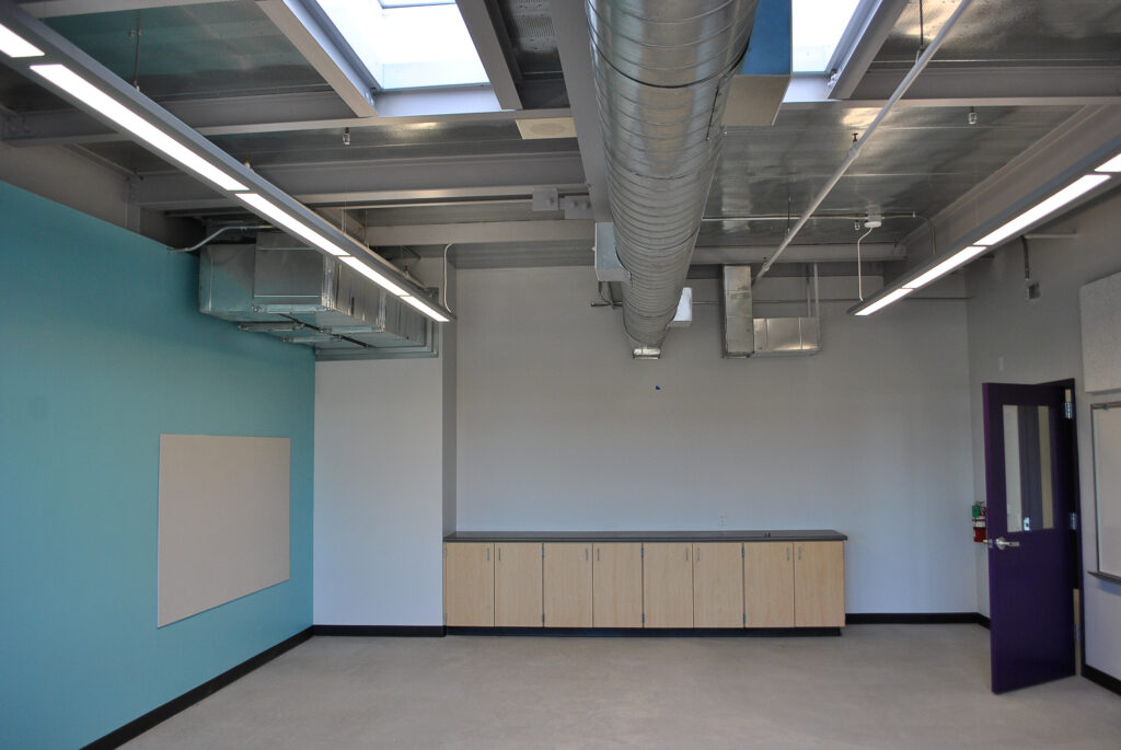 Interior of a classroom at Rocketship Senter Road Campus featuring modern lighting and ductwork.