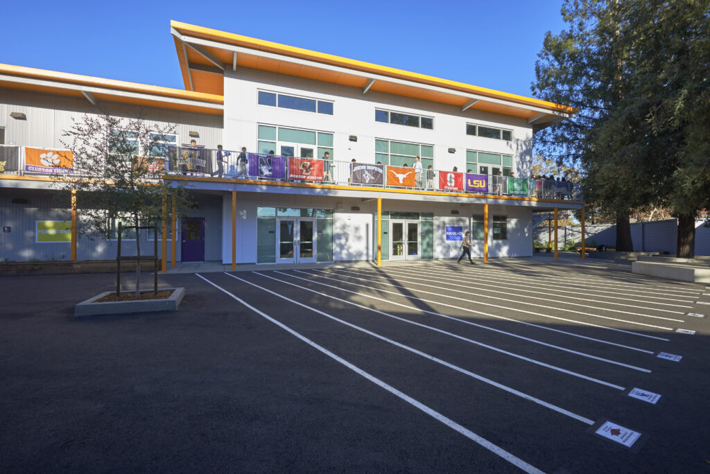 Exterior of Rocketship Senter Road Campus featuring a two-story building with banners and a student courtyard.