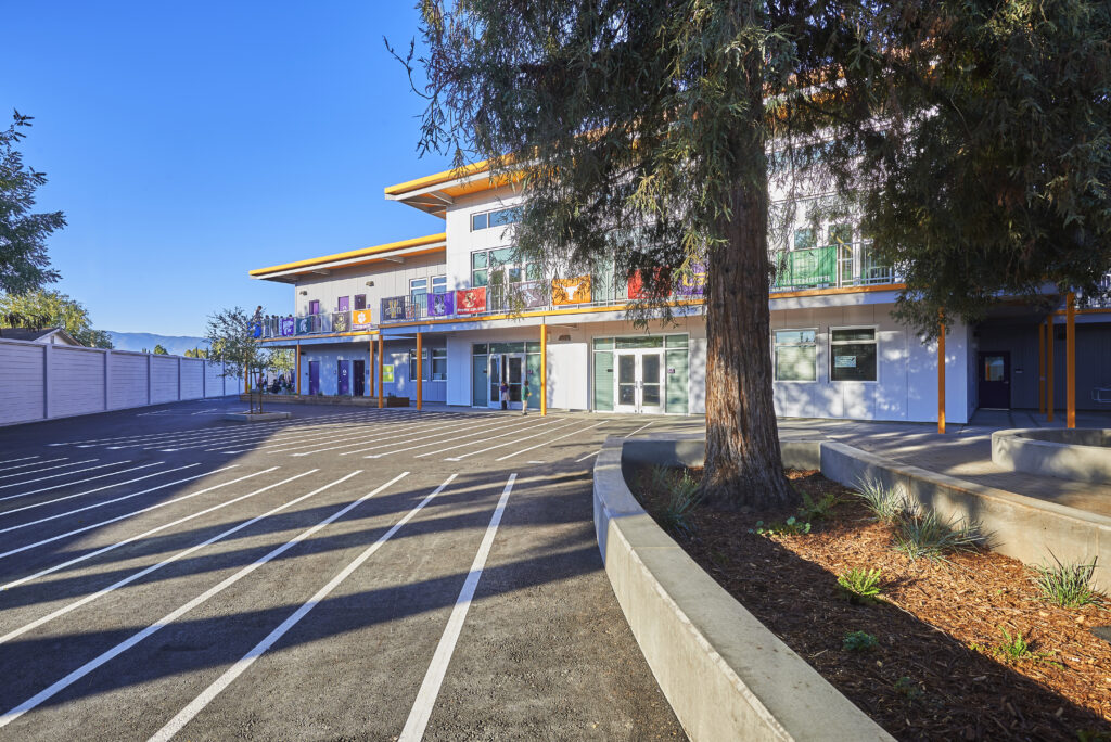 Front view of Rocketship Senter Road Campus with a two-story building and trees lining the student courtyard.