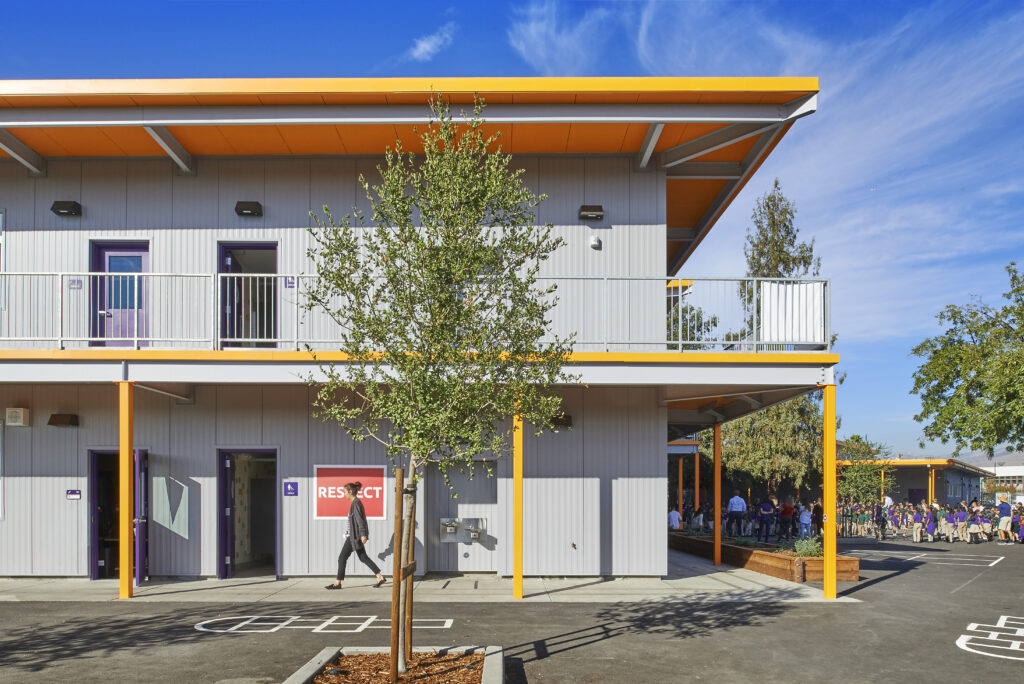 Exterior view of Rocketship campus, featuring a prominent "Respect" sign and orange accents, with students in the background.