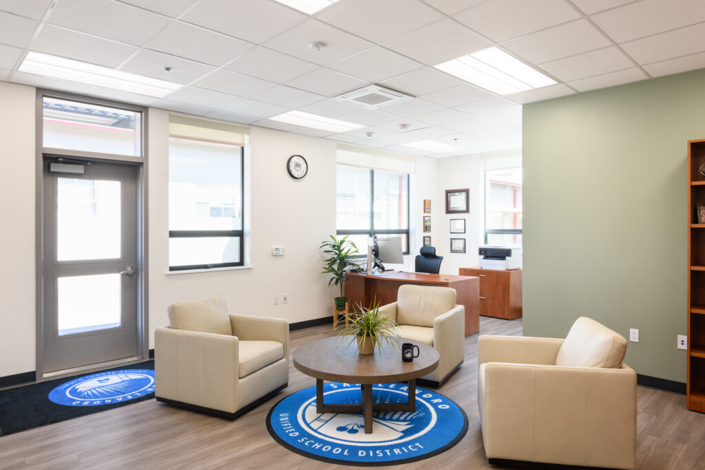 The professional reception and waiting area at the San Leandro USD headquarters, featuring modern seating, branded interior elements, and a dedicated administrative workspace.