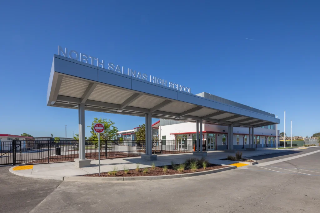 Exterior of North Salinas High School featuring a large grey metal entrance canopy with silver 3D signage.
